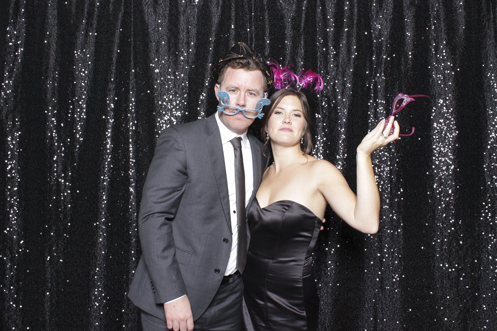 Couple with props at a black sequin backdrop