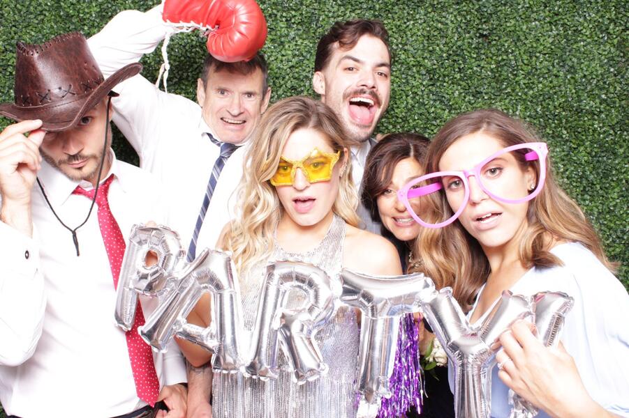Guests with fun props at a greenery wall
